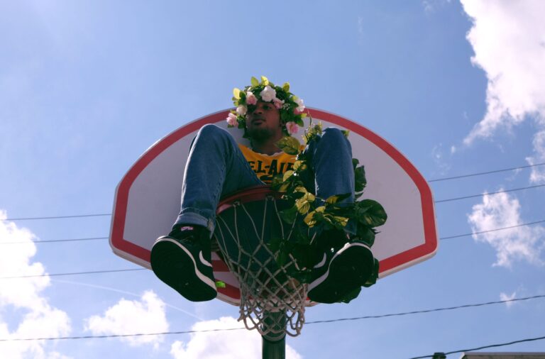 Person in basketball hoop wearing flower crown.