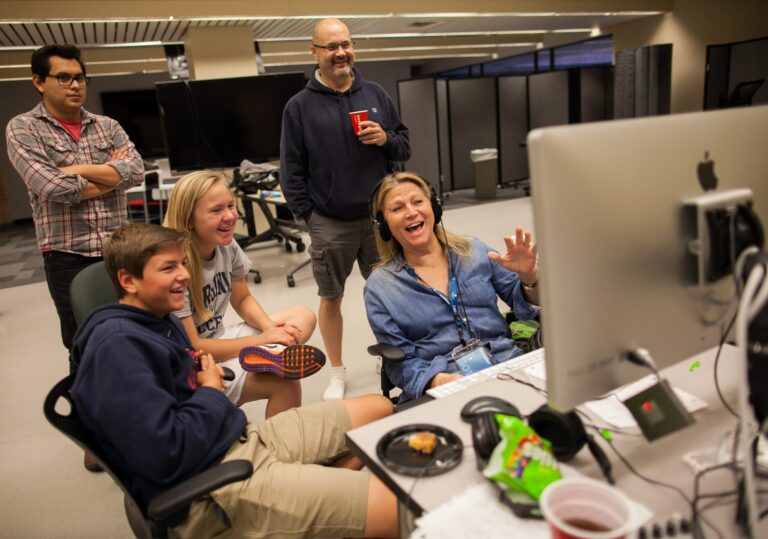 Group of people laughing and working on a computer.