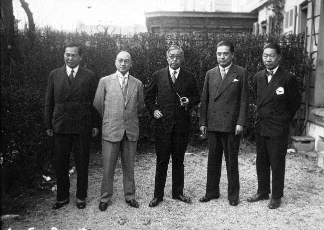 Group portrait of W. W. Yen and colleagues in suits, standing outdoors in front of a building and greenery.