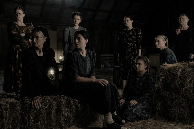 Group of women in dark dresses in "Women Talking" film scene.