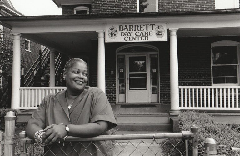 Woman in front of Barrett Day Care Center on West Main Street. Sign reads "Barrett Day Care Center.