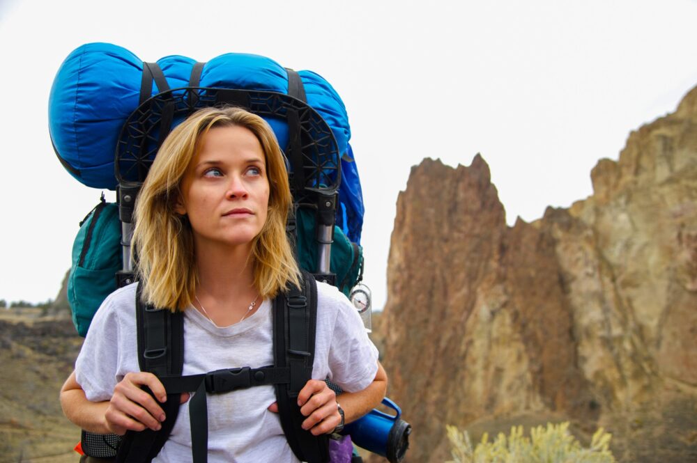 Reese Witherspoon as Cheryl Strayed in "Wild" backpacking through the desert landscape.