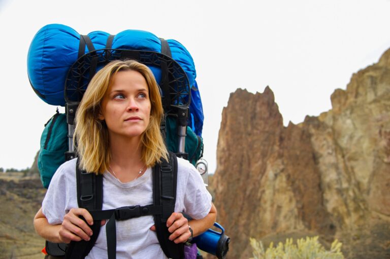 Reese Witherspoon as Cheryl Strayed in "Wild" backpacking through the desert landscape.