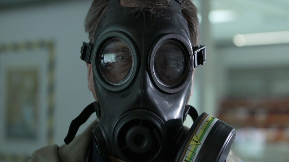 Man wearing a black gas mask, potentially related to chemical warfare.