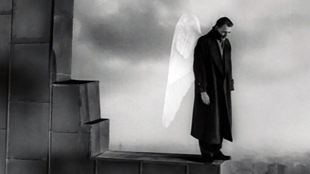 A man with angel wings standing on a ledge.