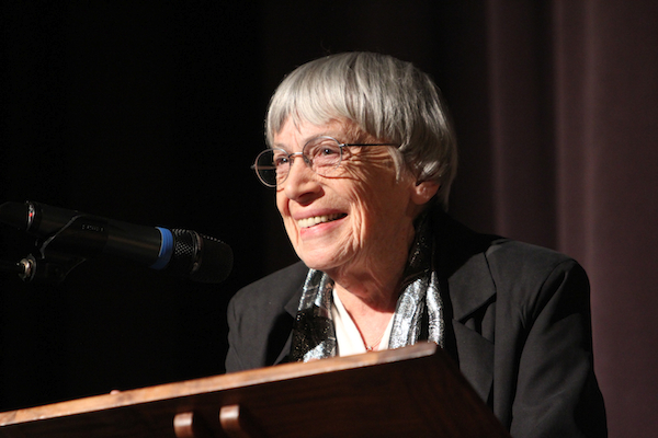 Ursula K. Le Guin smiles while speaking at a podium.
