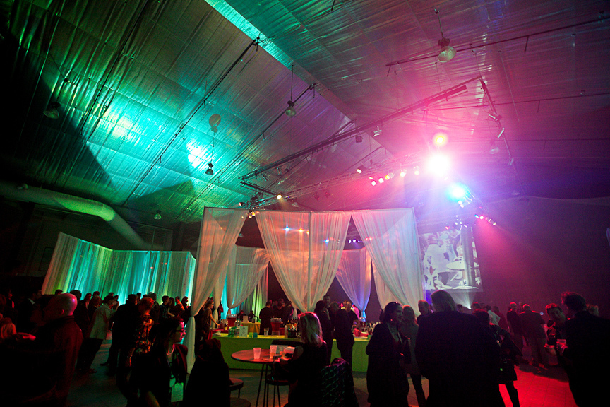 Late night wrap party with people under colorful lights in a large venue.