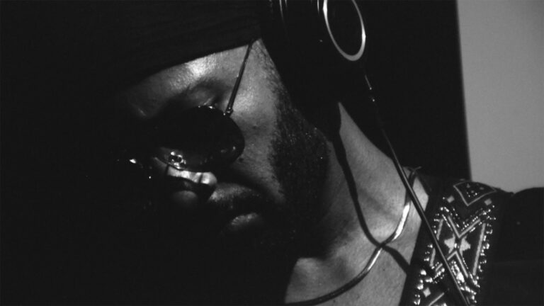 Kevin Jerome Everson in shadow, wearing headphones and sunglasses.