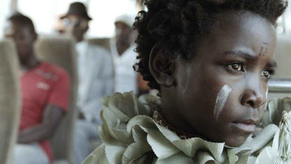 Young girl with face paint in "I Am Not a Witch," looking somber.