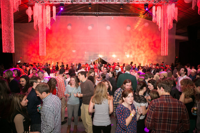 Crowded wrap party with red lighting and decorations.