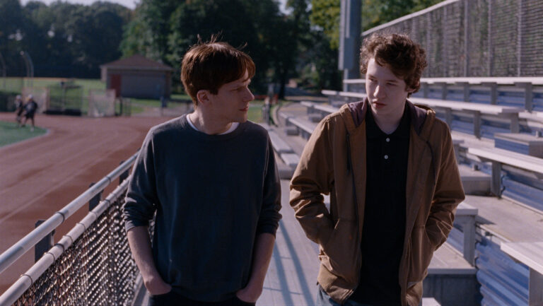 Two young men walk and talk on a track in Louder Than Bombs.
