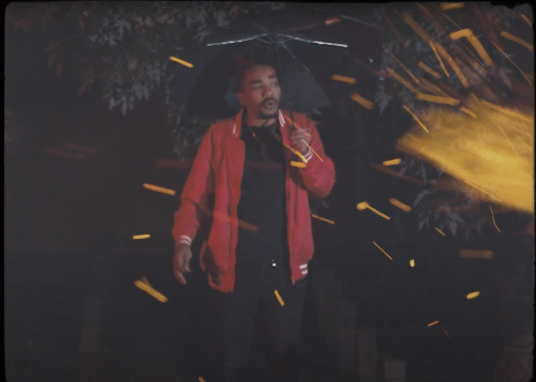 Man with umbrella in the Nine Pillars hip hop music video, surrounded by sparks.