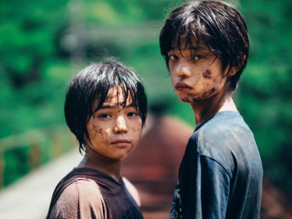 Two young boys with dirt on their faces stare intensely at the camera.