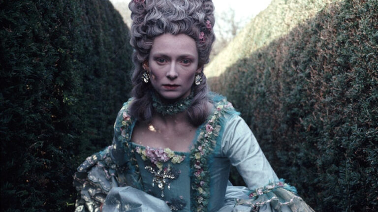 Tilda Swinton in Orlando costume: 18th-century style dress and powdered wig in a garden.