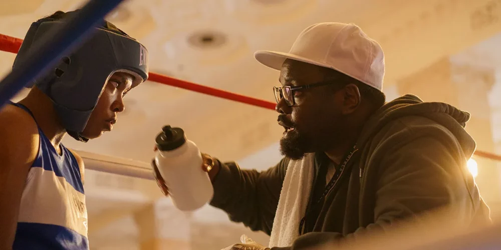 Boxer in ring listens to coach with water bottle. The Fire Inside.
