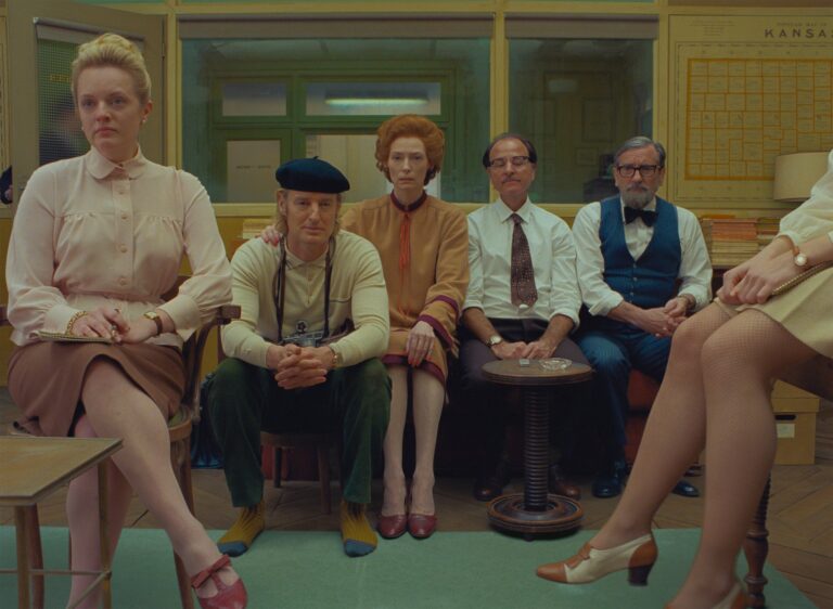Cast of The French Dispatch film sitting indoors