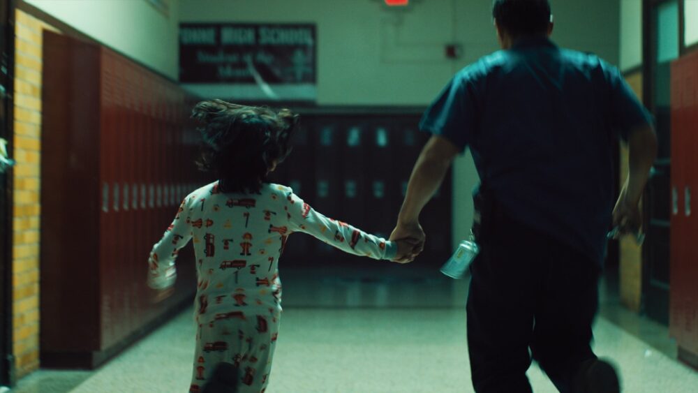 Child and adult run down school hallway. Dunne High School sign visible.