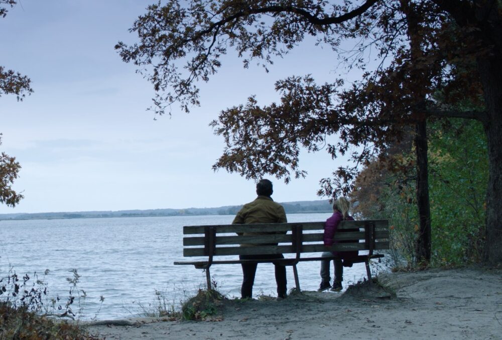 People on bench overlooking lake.