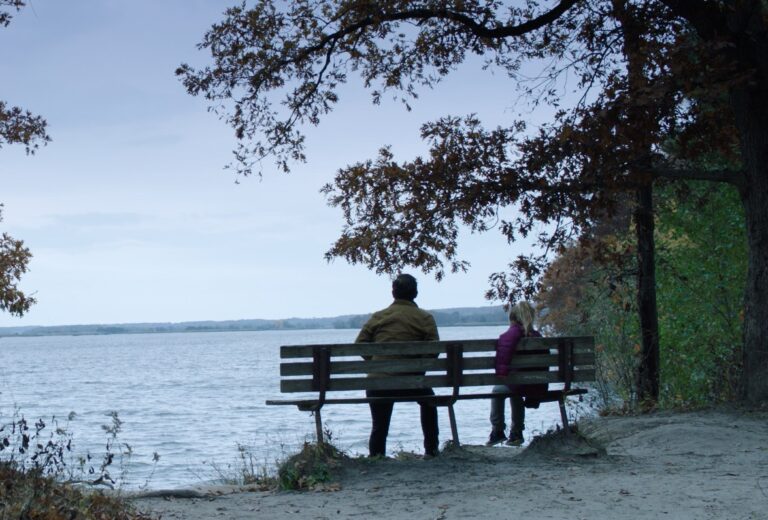 People on bench overlooking lake.
