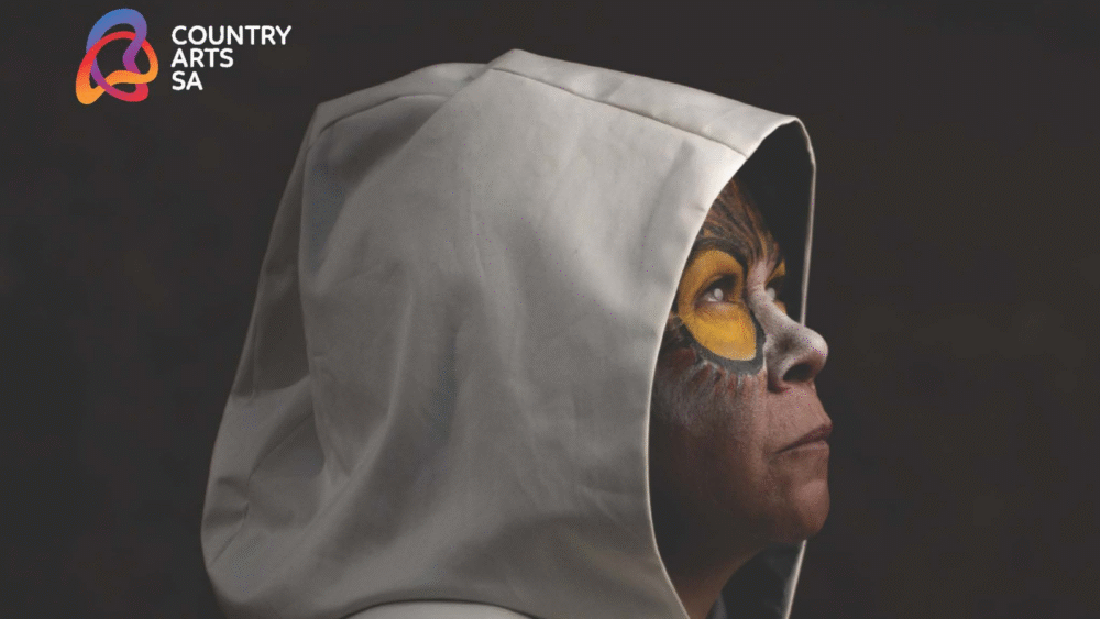 Person with face paint wearing a white hood, promoting Country Arts SA and Nunga Screen 2025.