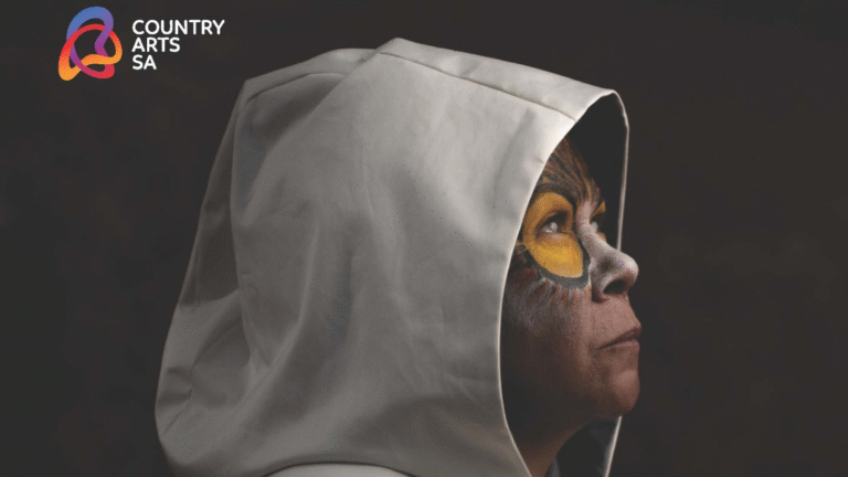Person with face paint wearing a white hood, promoting Country Arts SA and Nunga Screen 2025.