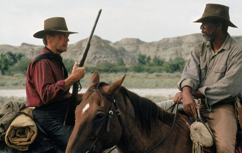 Clint Eastwood and Morgan Freeman in Unforgiven, riding horses in a western landscape.