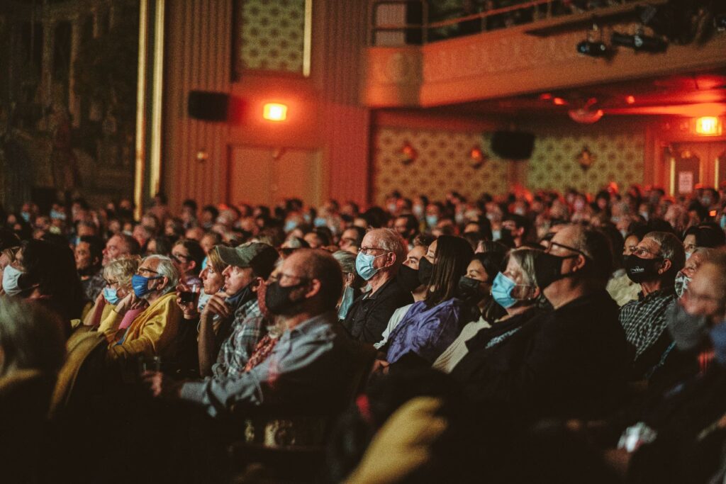 Audience wearing masks at NEA 2023 event in a theater.