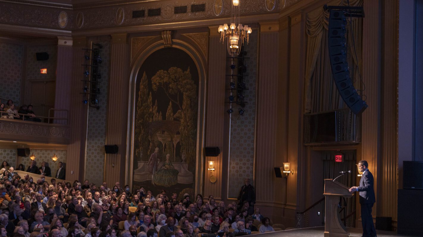 Audience listens to a speaker at the NEA 2024 event in a grand theater.