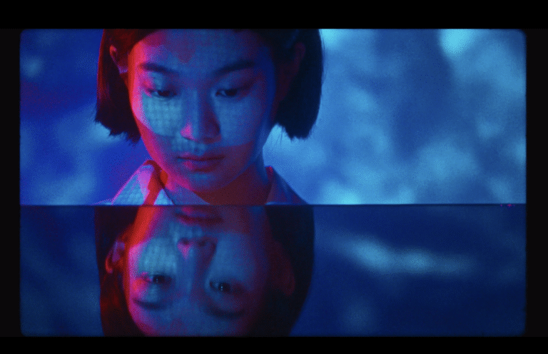 Girl with bob haircut reflected in water with blue and red lighting, reminiscent of A Brighter Summer Day.