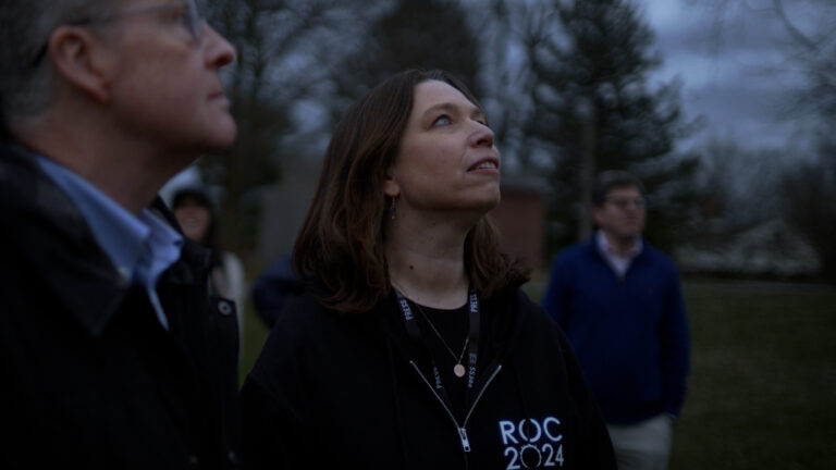 People looking up at the sky, wearing "ROC 2024" apparel.