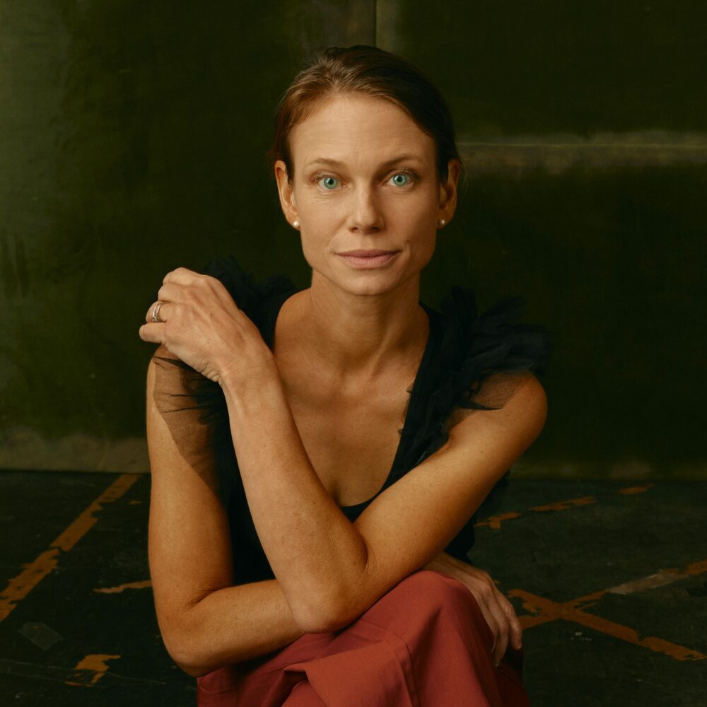 Portrait of Jessica Hargrave with arms crossed, wearing a black top and red pants.