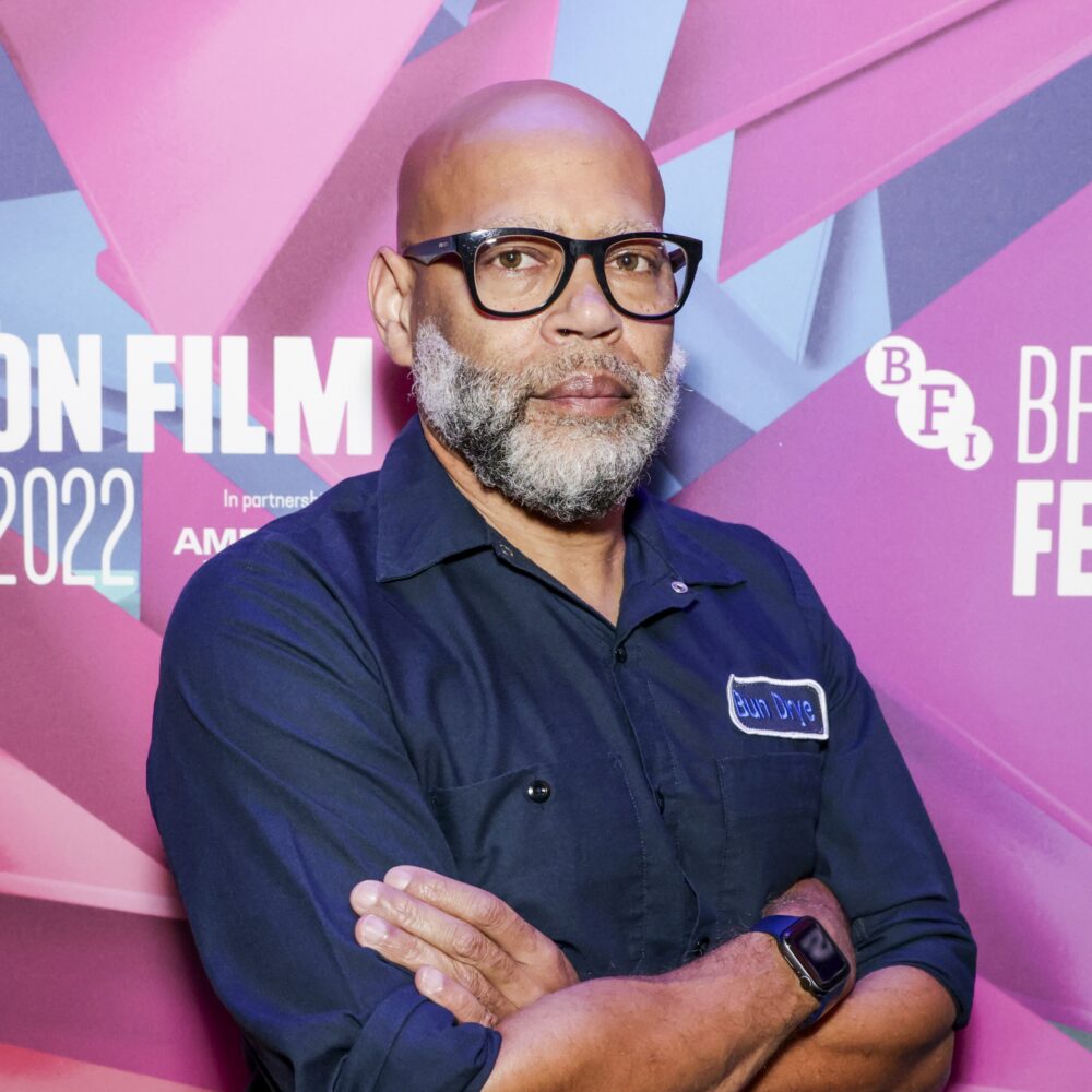 Kevin Jerome Everson at a film festival, wearing glasses and a dark shirt with arms crossed.