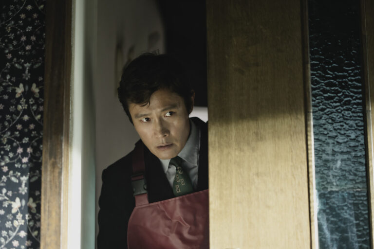 Man in apron peeking through doorway in 