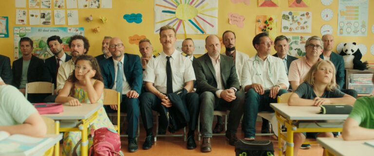 Classroom scene with adults and children sitting at desks.