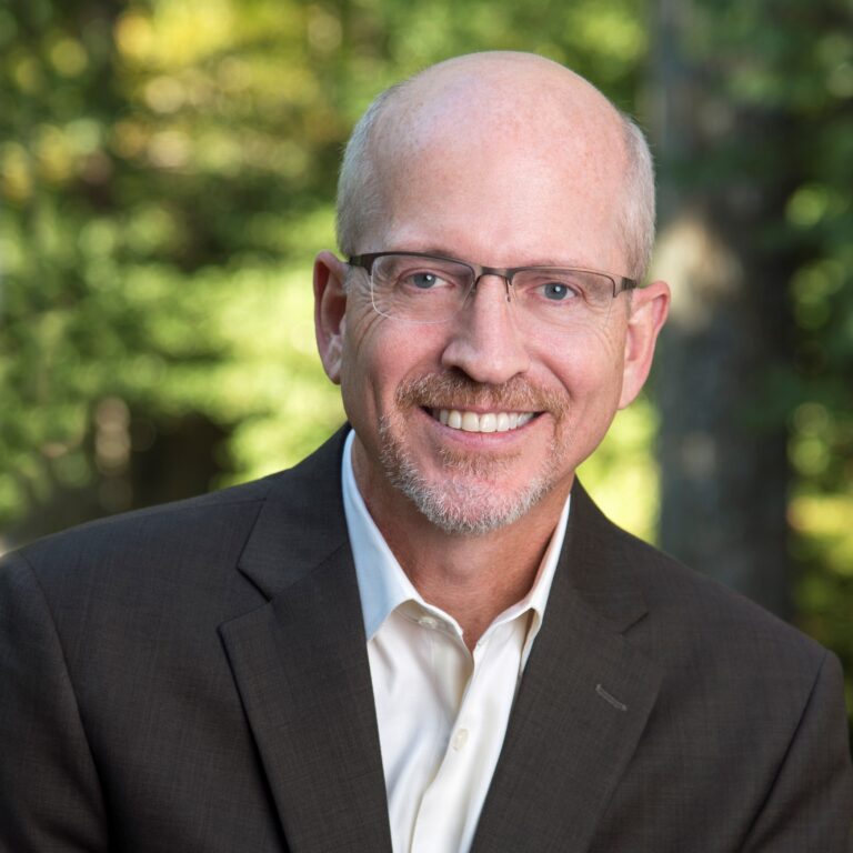 Ron Culberson, speaker and author, smiling in a suit against a green background