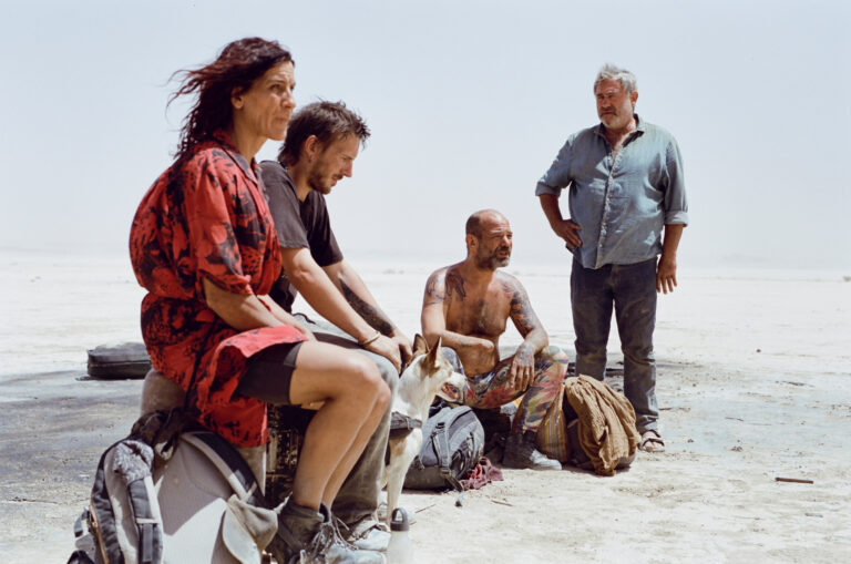 Group of people and a dog resting in a desolate landscape, possibly related to the movie 