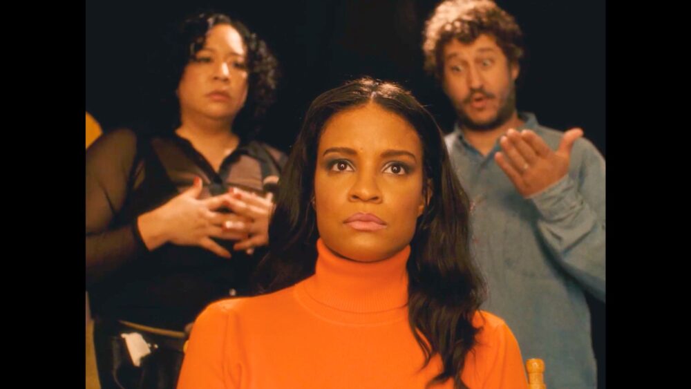 Actress in orange turtleneck with director and crew on TV set. Street Smart.