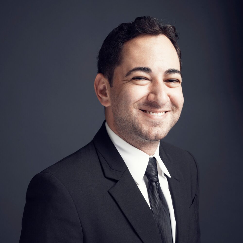 Scott Feinberg in a suit and tie smiling confidently