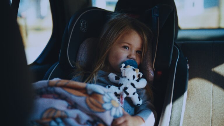 Child in car seat with pacifier and stuffed animal, leaving the light.
