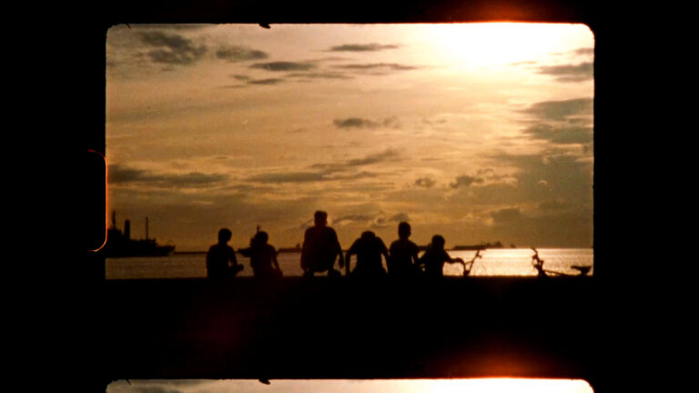 Silhouette of children watching a sunset over the water.