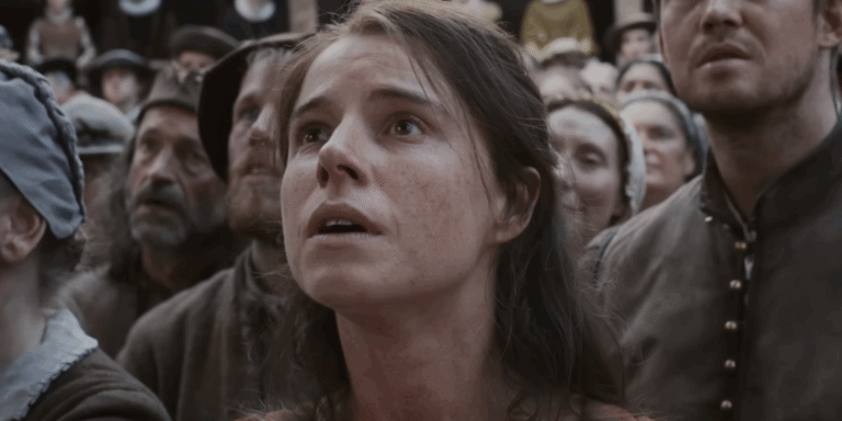 Still from 'Hamnet' showing a woman in period clothing looking upwards with a crowd of people.