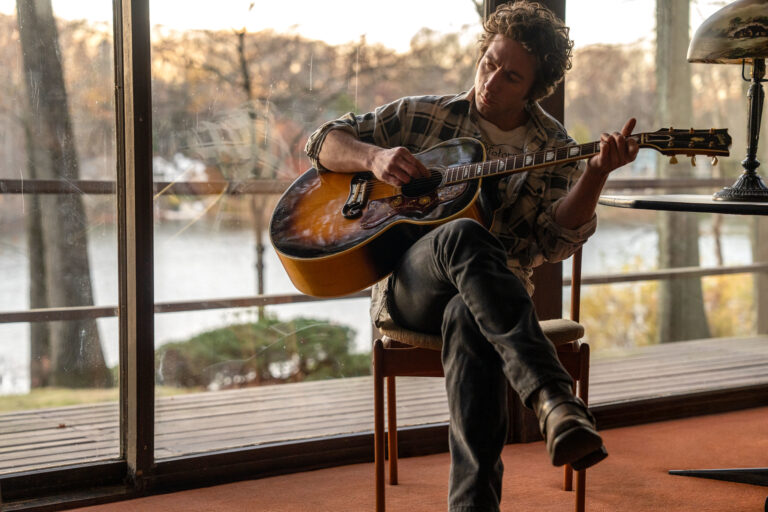 Scene from SPRINGSTEEN: DELIVER ME FROM NOWHERE. Man plays guitar in a sunlit room.