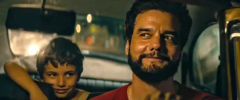 Film still from THE SECRET AGENT. Man and child in a taxi, smiling.