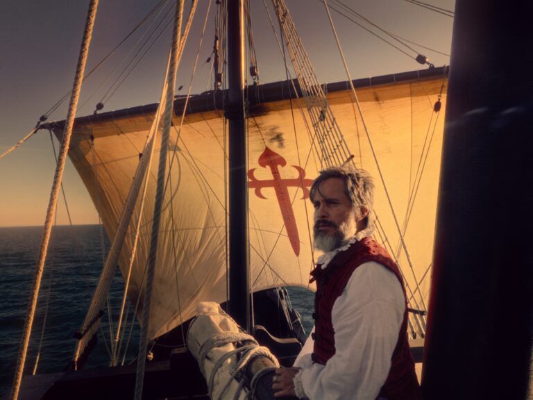 Film still from MAGELLAN. Magellan on a ship, gazing at the horizon.
